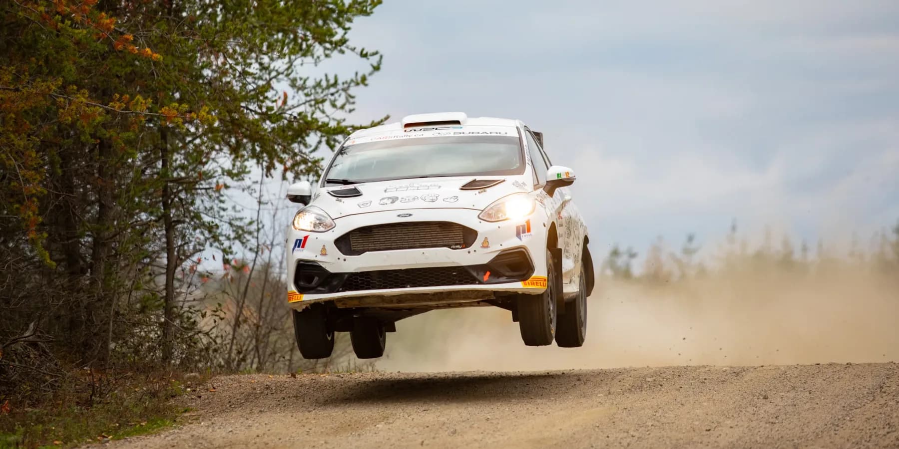 Voiture de rallye en plein saut sur une spéciale en gravier, au Rallye de Charlevoix