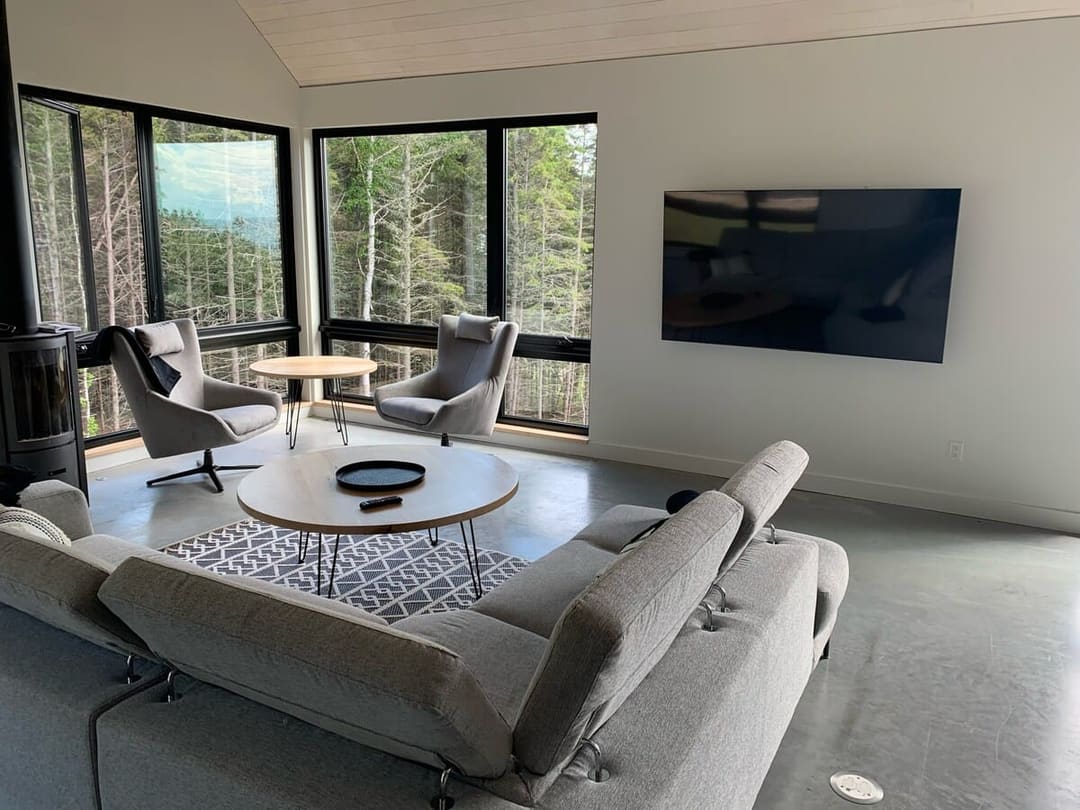 Salon dépouillé avec fauteuils gris et vue forêt, Les Thermes