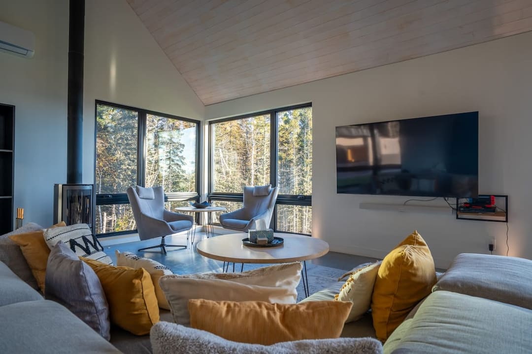 Salon avec poêle à bois en angle et fauteuils gris, Les Thermes